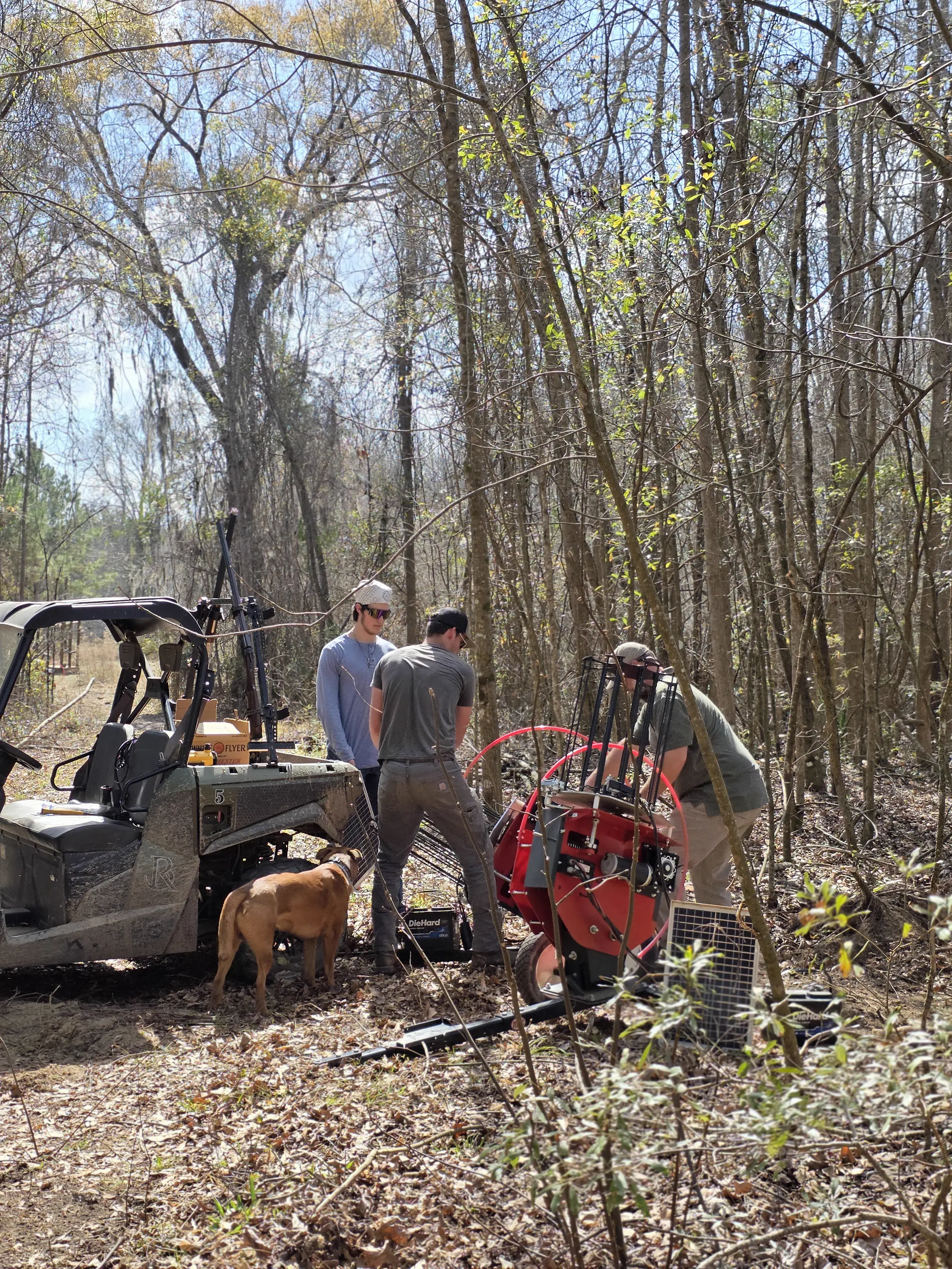 Crew working on trap machine setup with ATV nearby