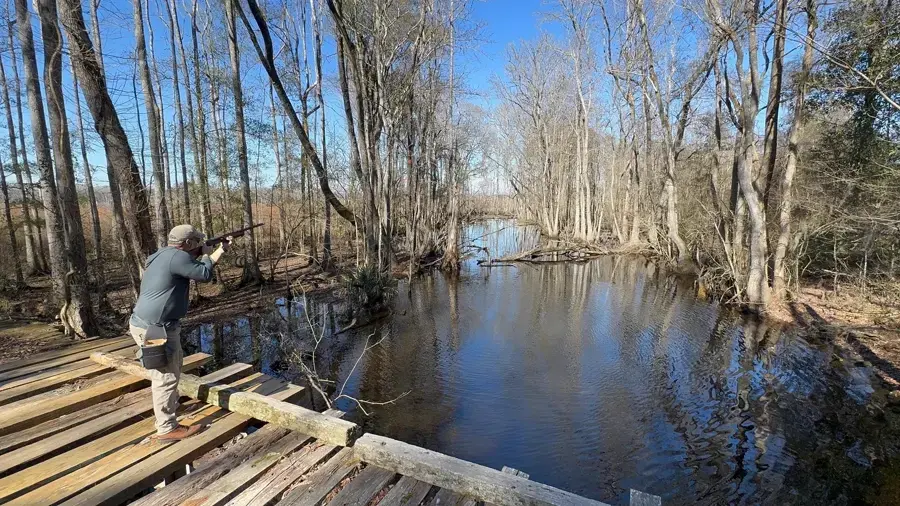 A shooter on a deck stand along the river at Traditions Field Club